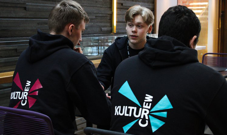 Tre tonårspojkar med svarta hoodies med tryck på ryggen: KulturCrew