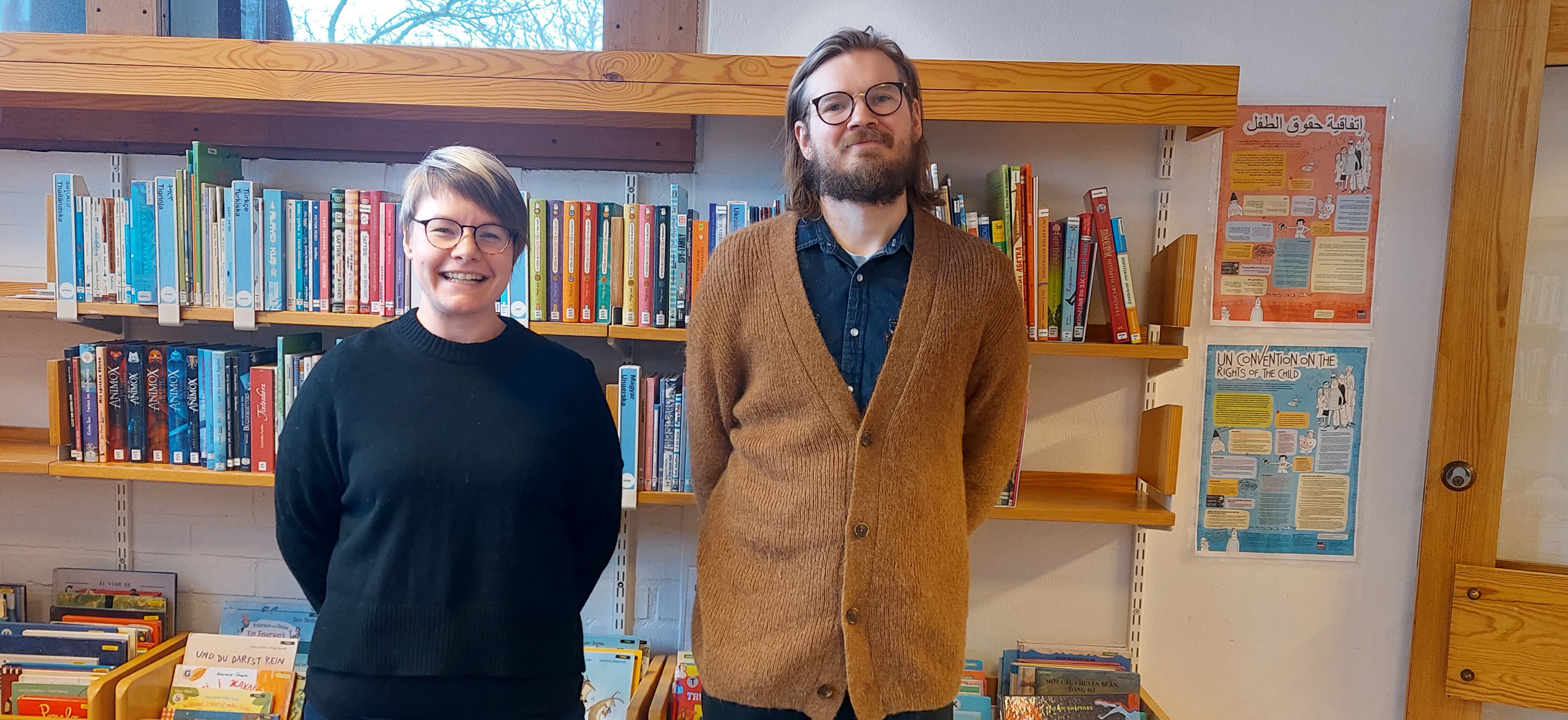 Bibliotekarierna Caroline och Oskar står framför en hylla med barnböcker