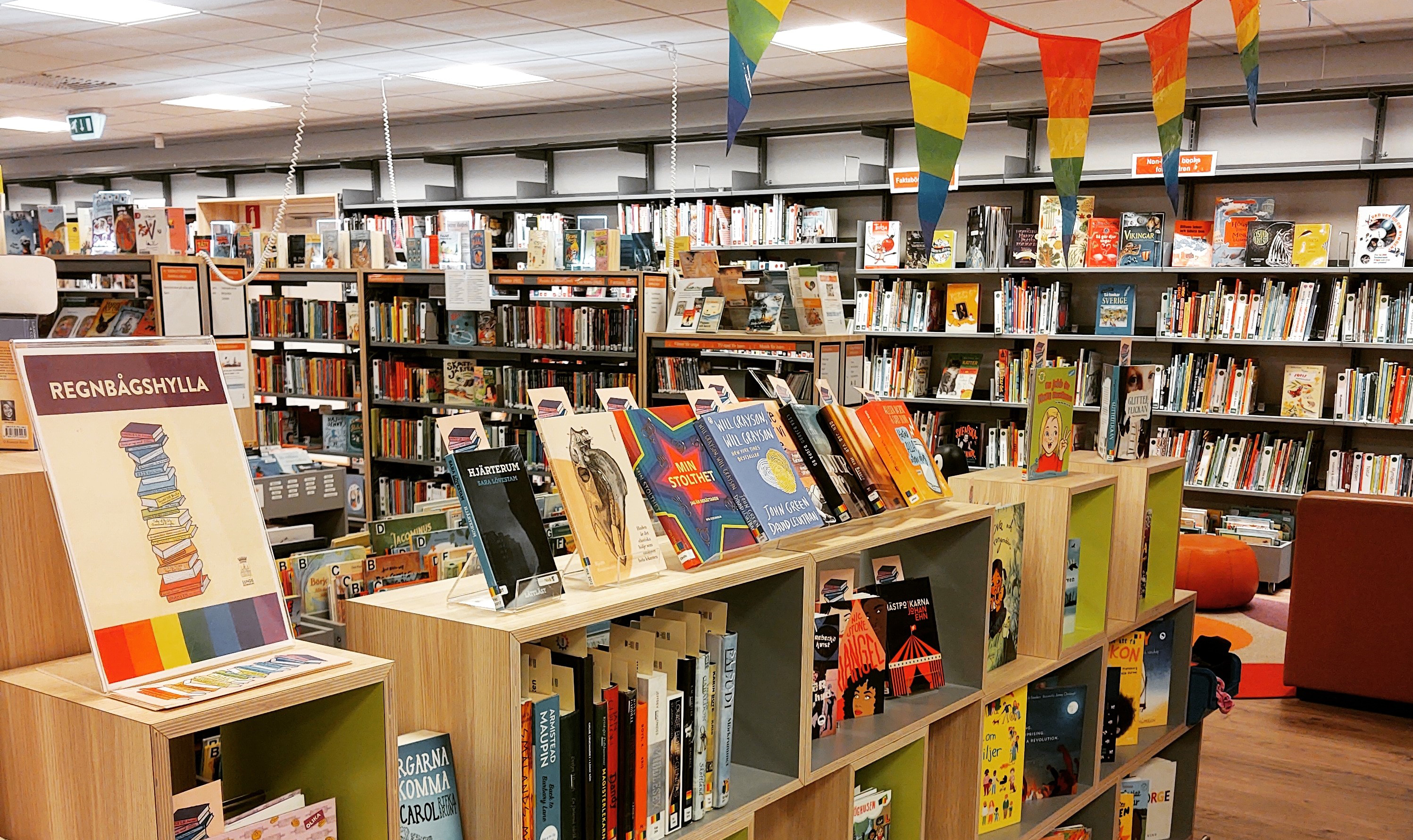 Regnsbågshylla med böcker och skyltar på bibliotek