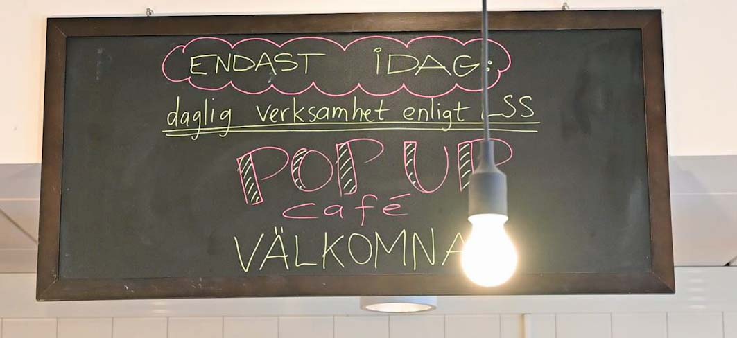 Text på en svart krittavla: Daglig verksamhet pop up café