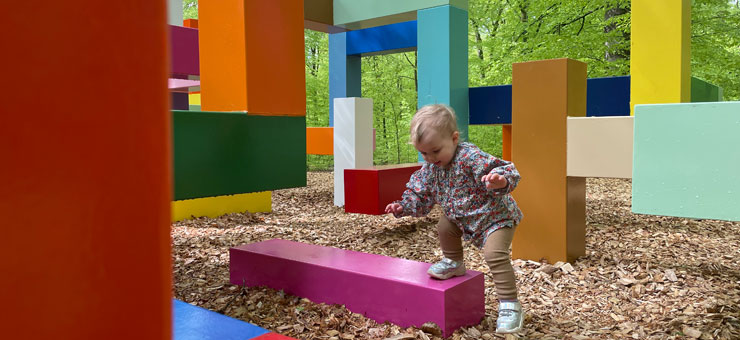 Ett litet barn leker med färgglada klossar i en skog