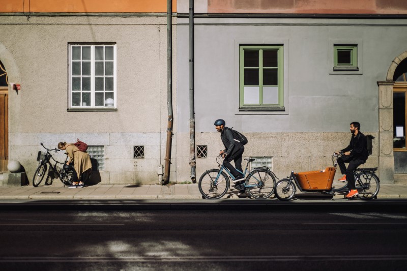 Tre personer cyklar i stadsmiljö.