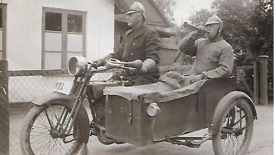 En svartvit bild från 1920talet. Två brandmän på en motorcykel med sidovagn.