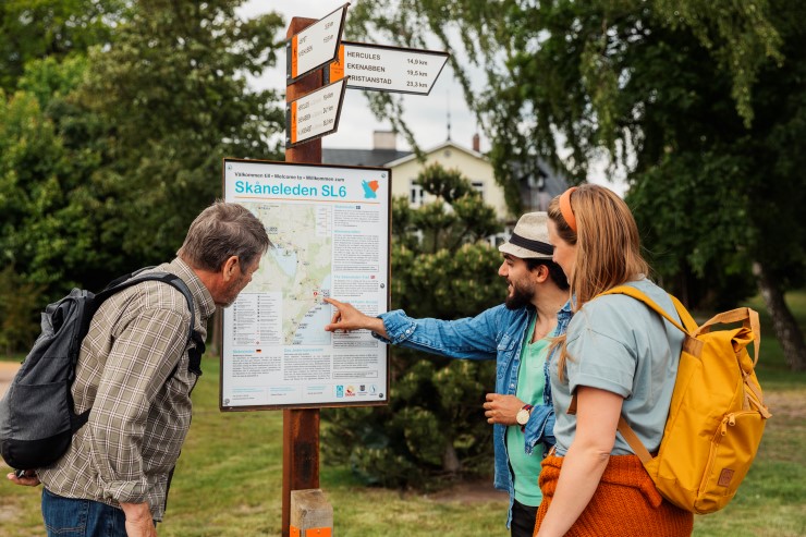 Tre personer pekar på en karta.