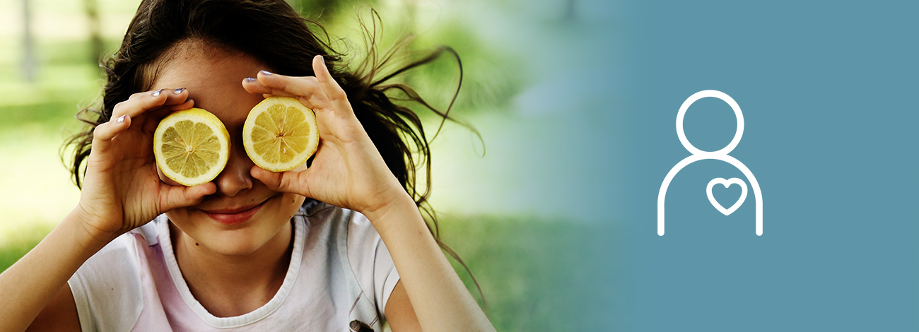 Flicka håller citronskivor framför ögonen och ler