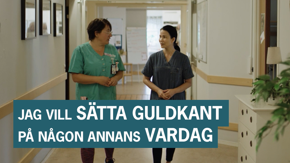 Två kvinnor i sjukhuskläder pratar med varandra.