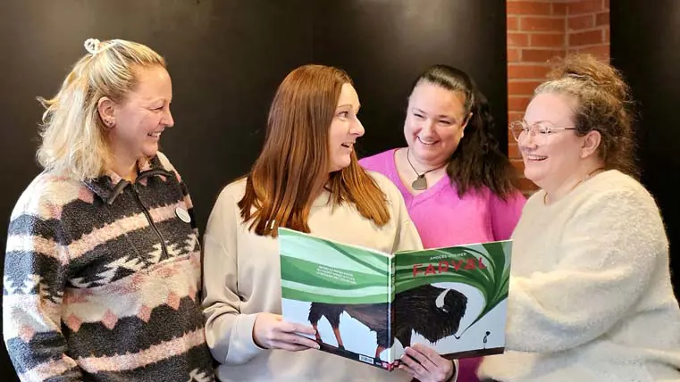 fyra kvinnor ler, tittar på varandra och i en bilderbok