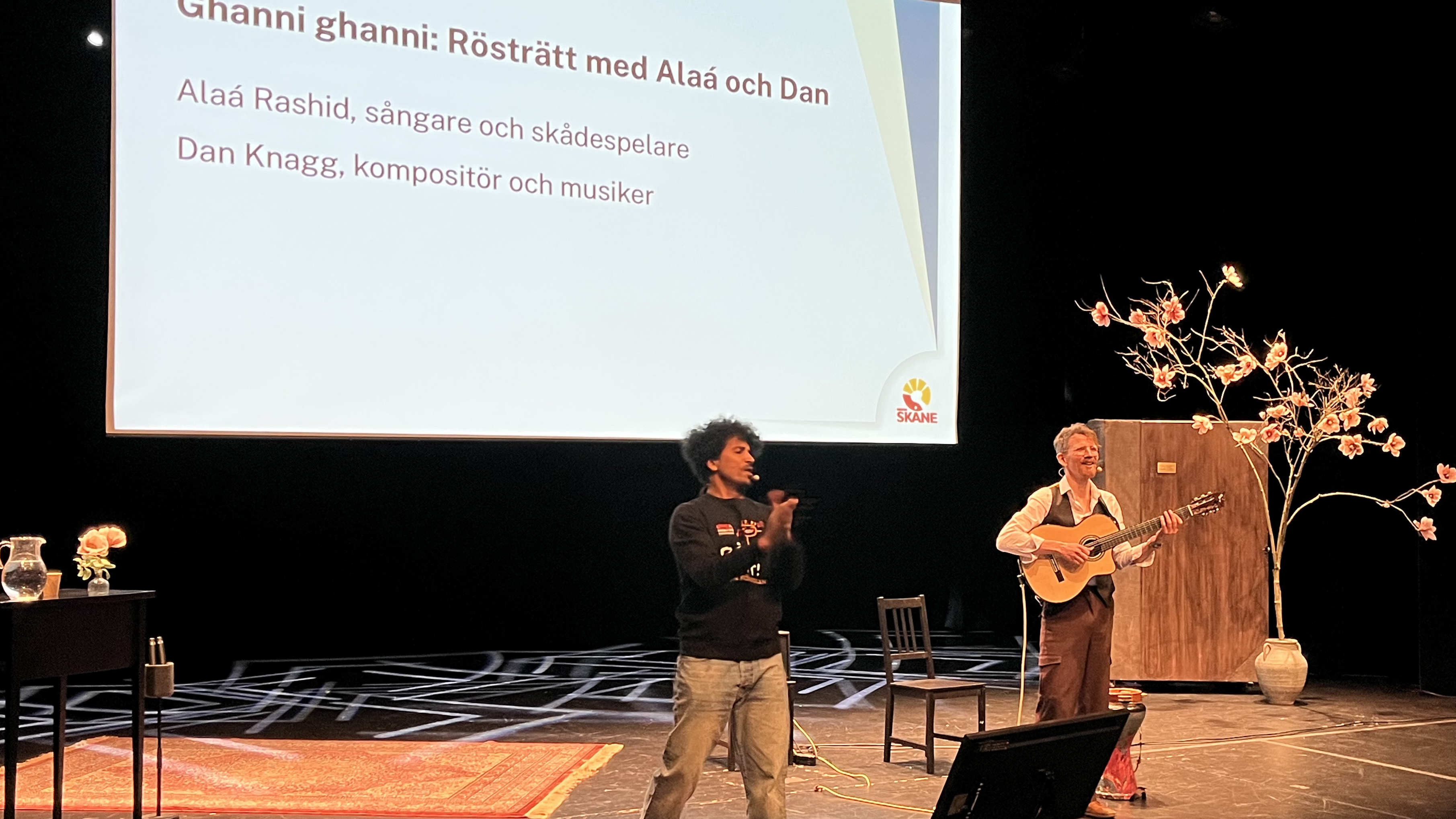 Två musiker står på en scen och spelar och sjunger