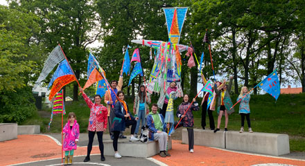 En grupp människor står i färgglada kläder och håller färgglada flaggor i händerna.