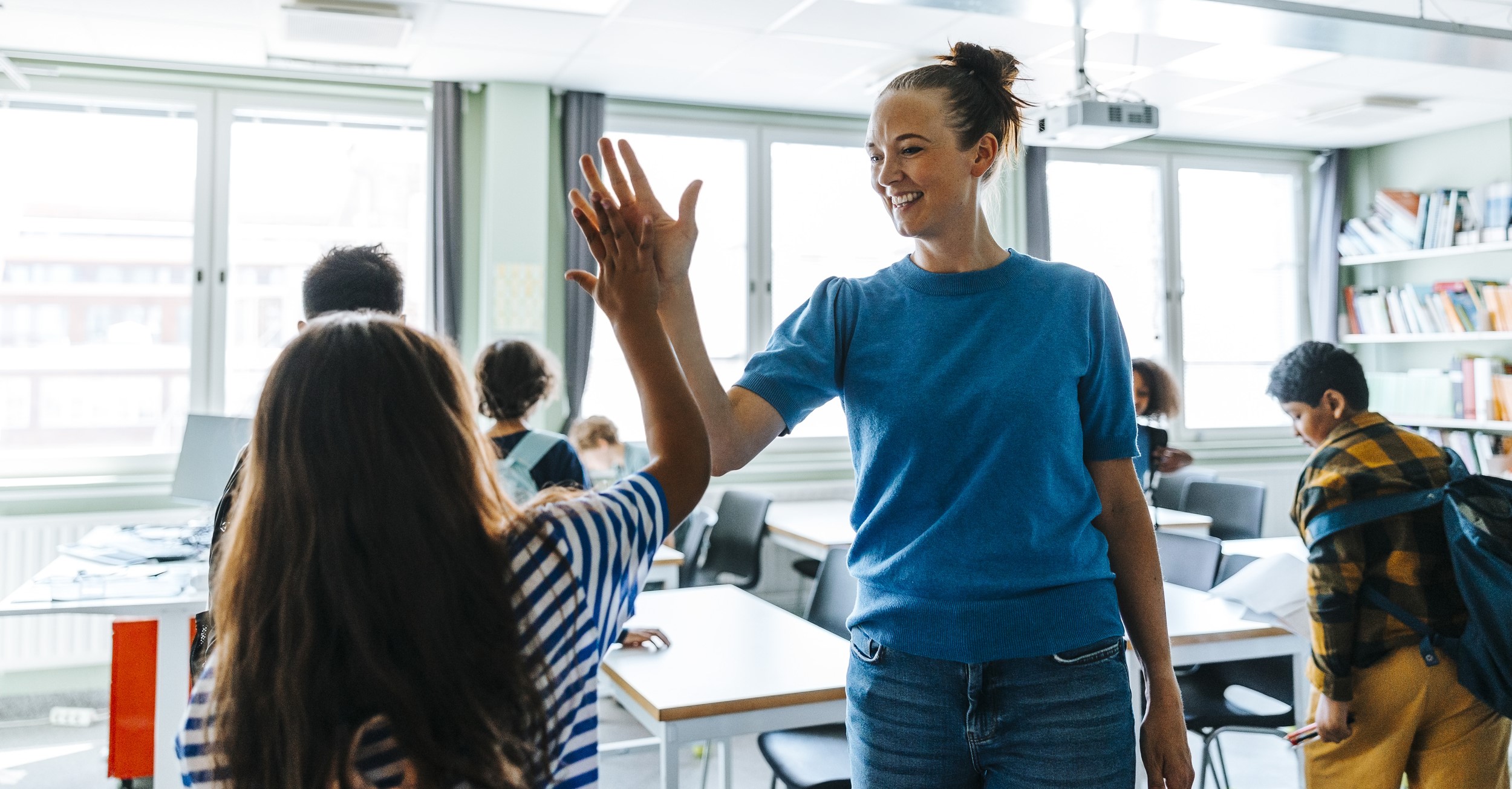Lärare som står i klassrum med elev.