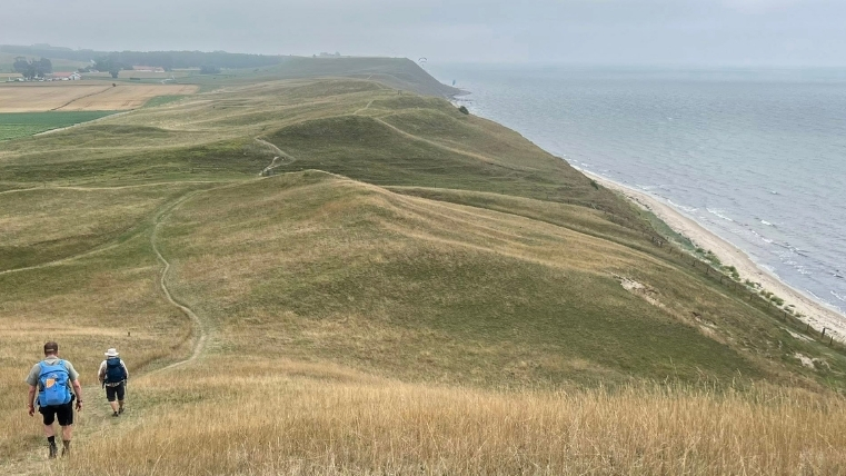 Bild på vandrare i skånskt landskap.