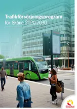 Tre personer står vid busshållplats och väntar på den gröna bussen som kommer.