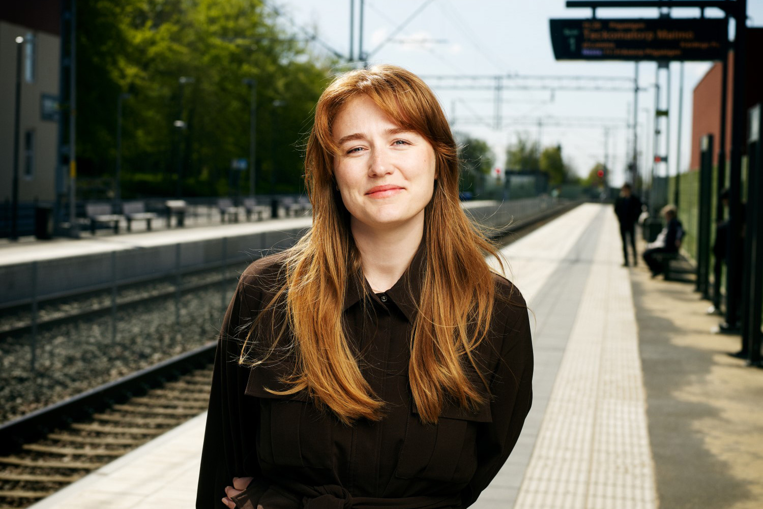 Porträtt av Nellie Stenvall. I bakgrunden en tågperrong.