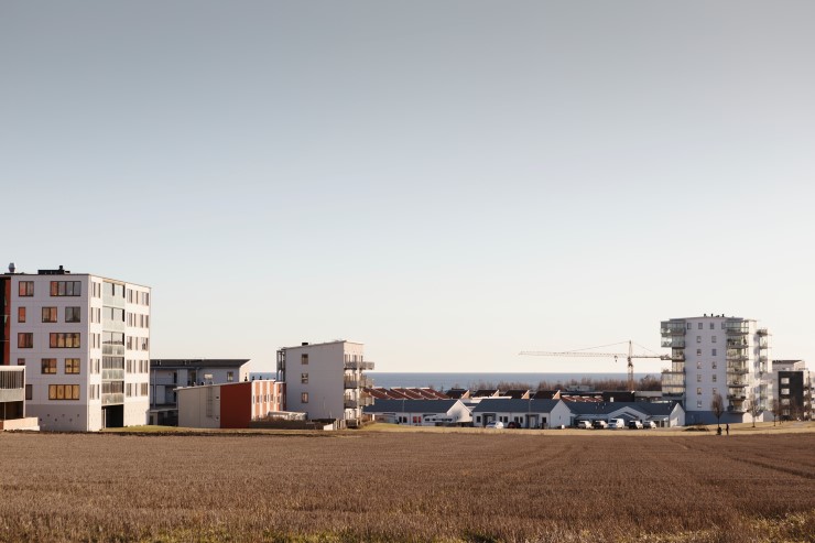 Lägenhetshus på en åker framför havet.