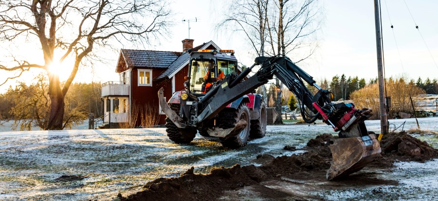 Internetkablar grävs ner intill ett rött hus med vita knutar