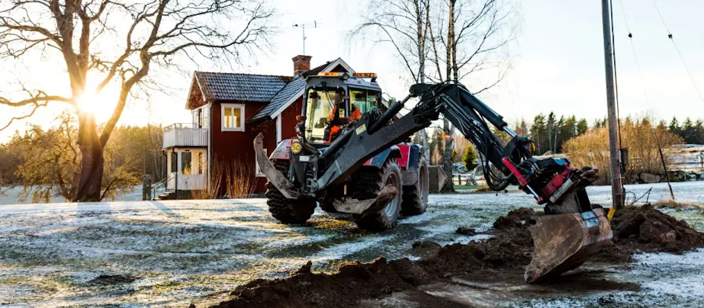 Internetkablar grävs ner intill ett rött hus med vita knutar