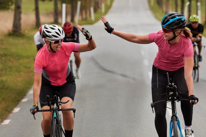 Cyklister gör high five på landsväg
