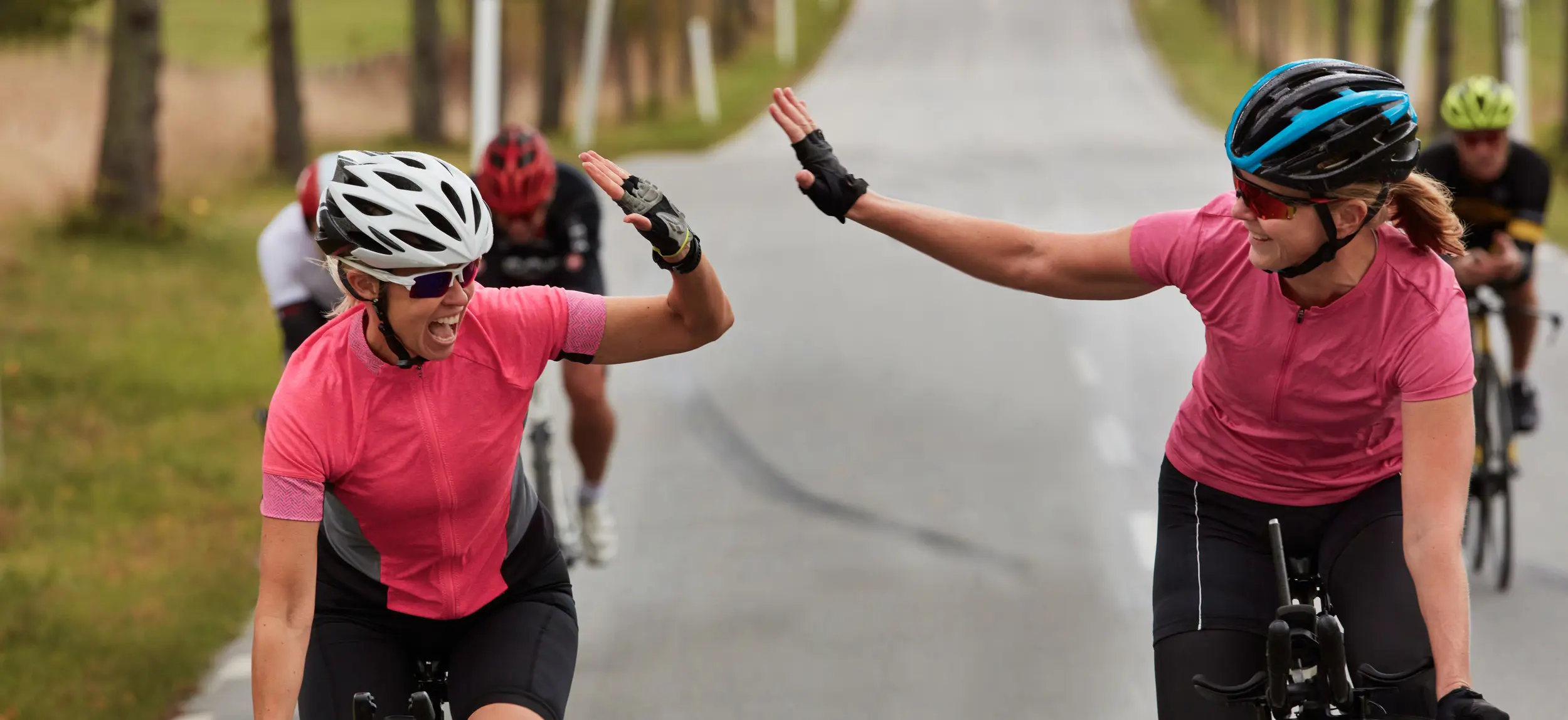 Cyklister gör high five på landsväg