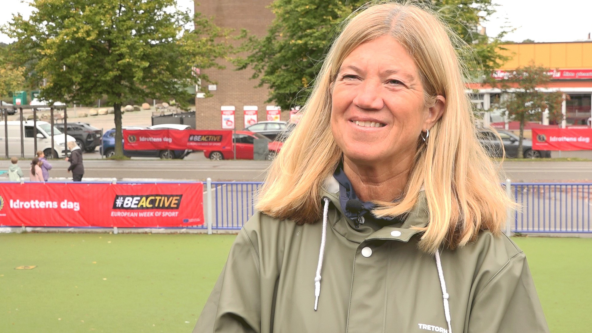 Kvinna i grön regnjacka kisar. 