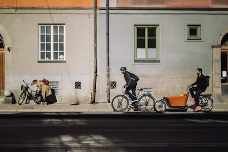 Tre personer cyklar i stadsmiljö.