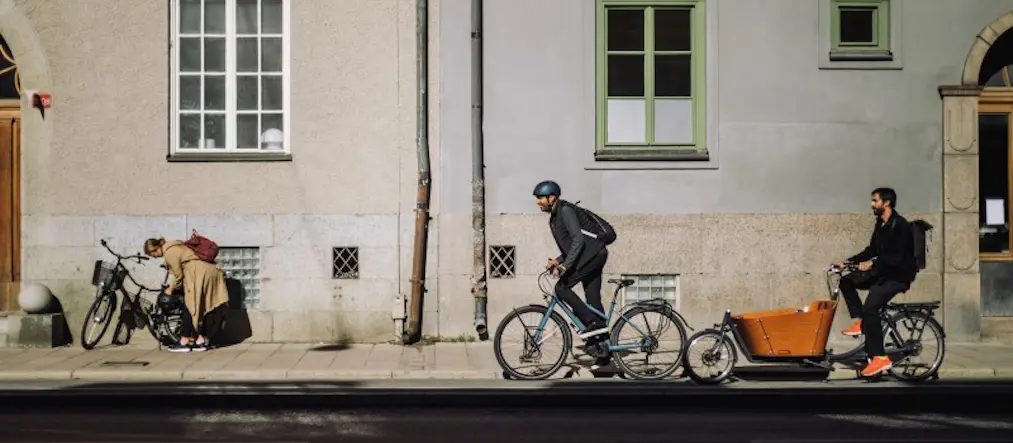 Tre personer cyklar i stadsmiljö.