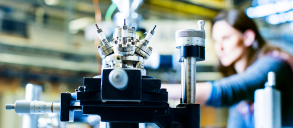 Kvinna står bakom industrirobot.