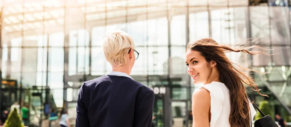 Två personer på väg mot stationsbyggnad.