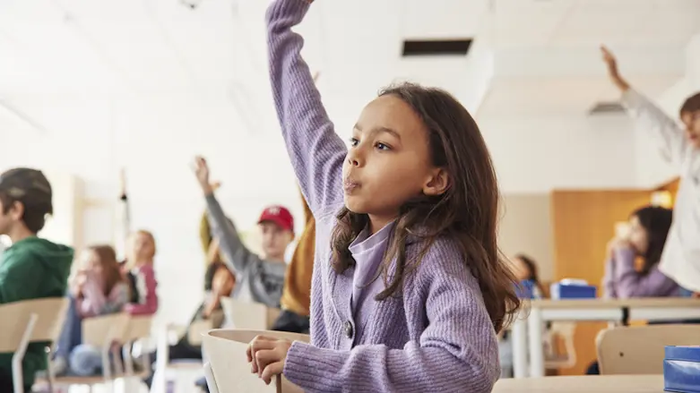 Barn i grundskolan i ett klassrum. Flera har händerna uppräckta.