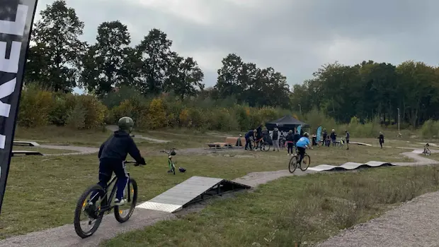 Två barn cyklar på träbana som slingrar sig fram i naturen.