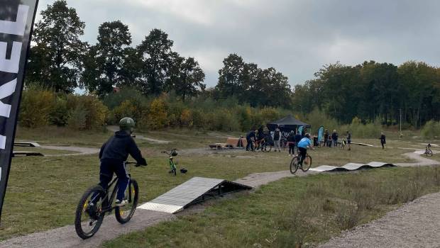 Två barn cyklar på träbana som slingrar sig fram i naturen.