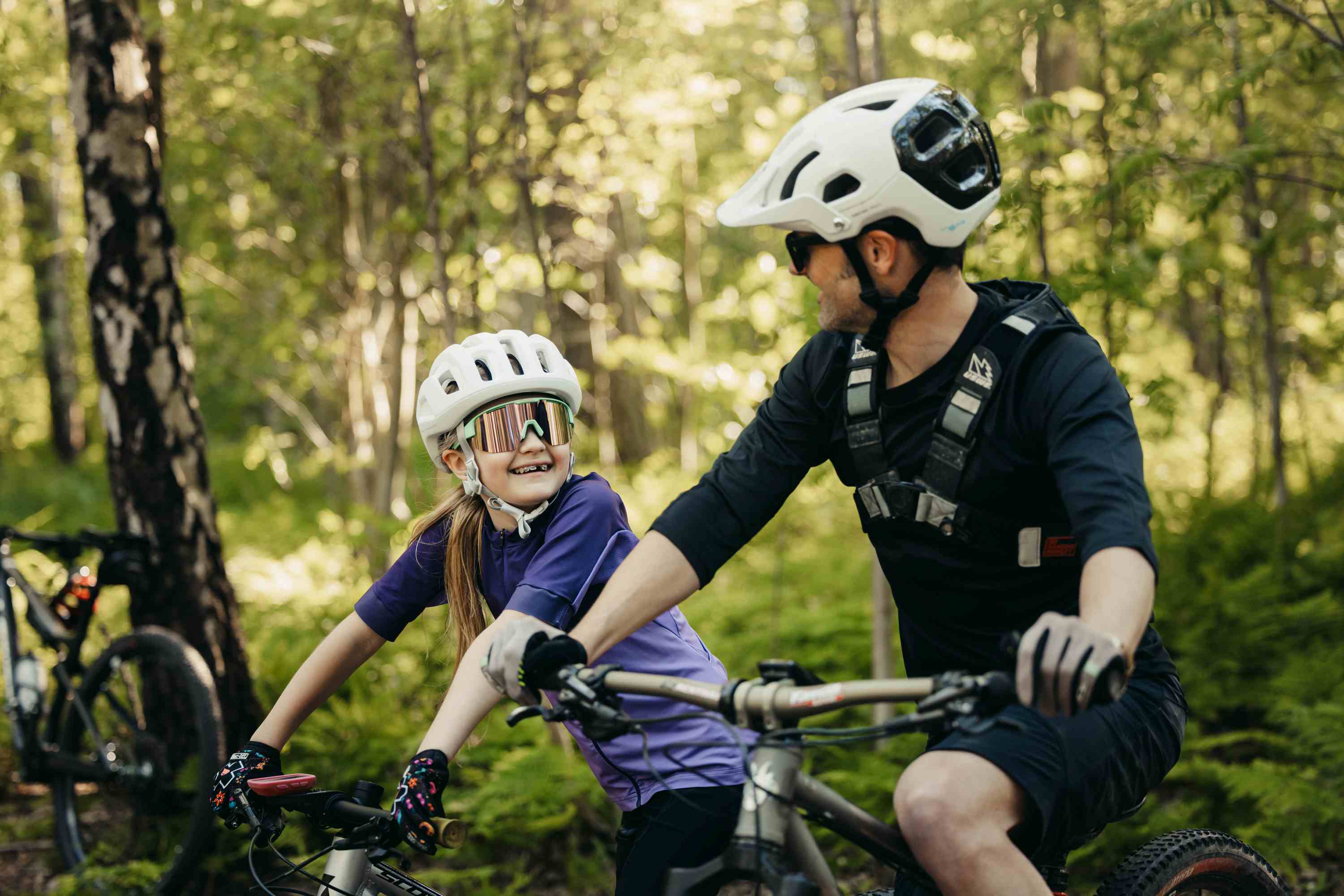 Förälder och barn som cyklar mountainbike i skogen.