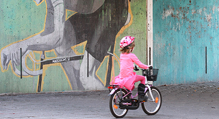 barn i rosa kläder och hjälp på väg på cykeln